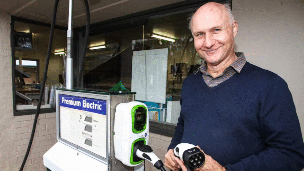 Mick Harris holding a new electric charging pump installed into an old petrol pump